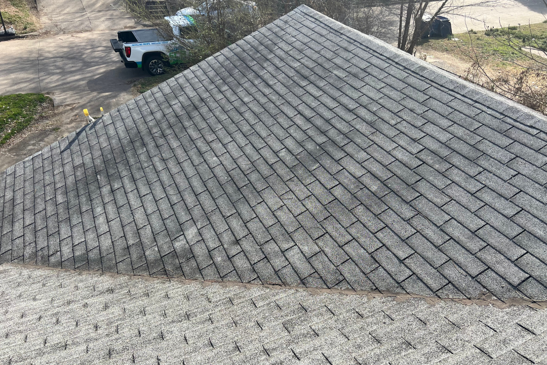 Aerial two-section contrast — dark algae-stained older shingles vs clean new shingles, GCR truck in background