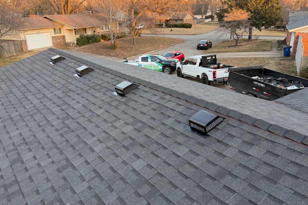 Four box vents properly spaced on fresh dark shingle roof — GCR truck clearly visible in driveway, dump trailer, golden hour
