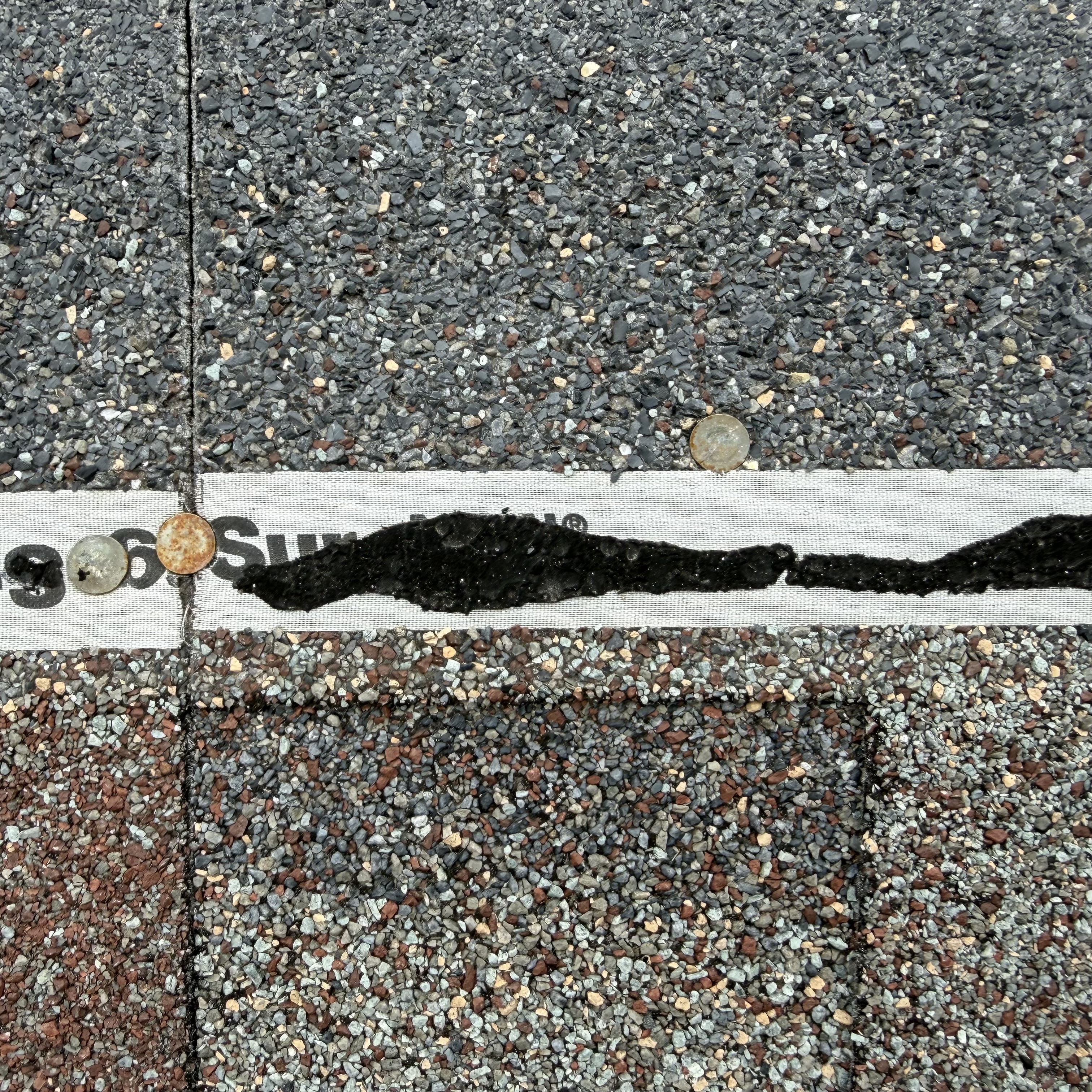 Failed seal strip on shingle — black sealant split wide open, two rusted nail heads visible, Summit underlayment tape showing
