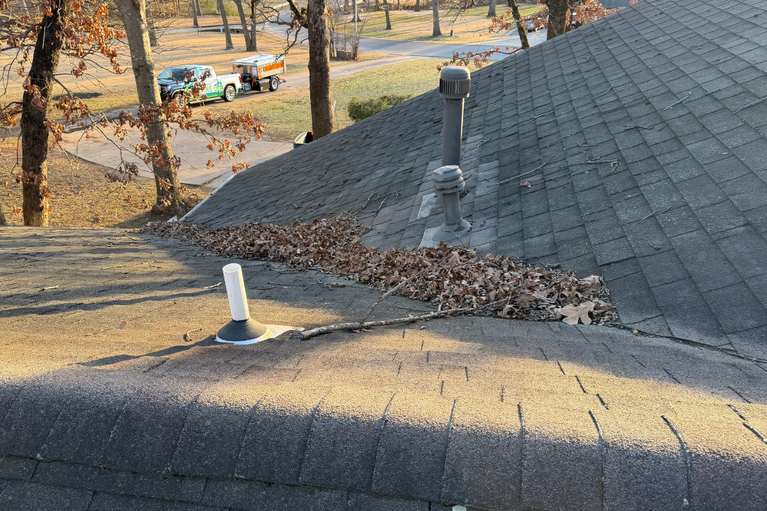 GCR truck + Equipter RB4000 on street — leaves and debris piled in roof valley, tree branches on roof, pipe jacks in frame