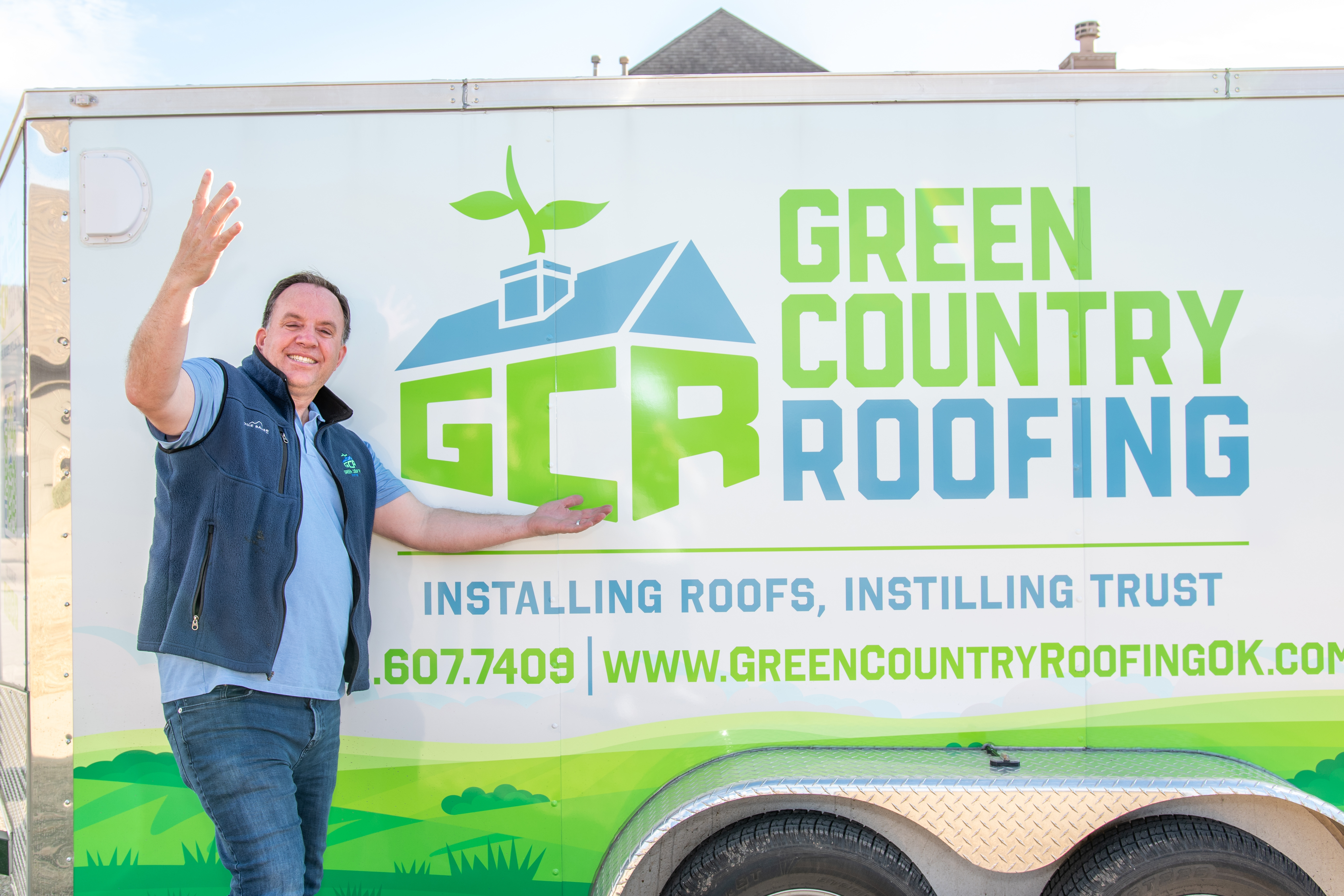 Rob Moore next to the Green Country Roofing trailer