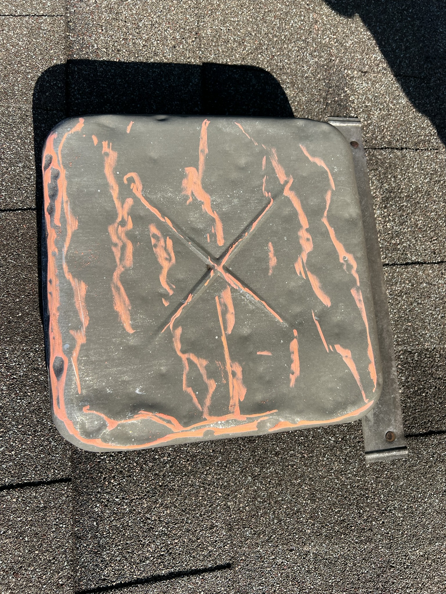 Heavily dented box vent with orange adjuster paint marking hail damage