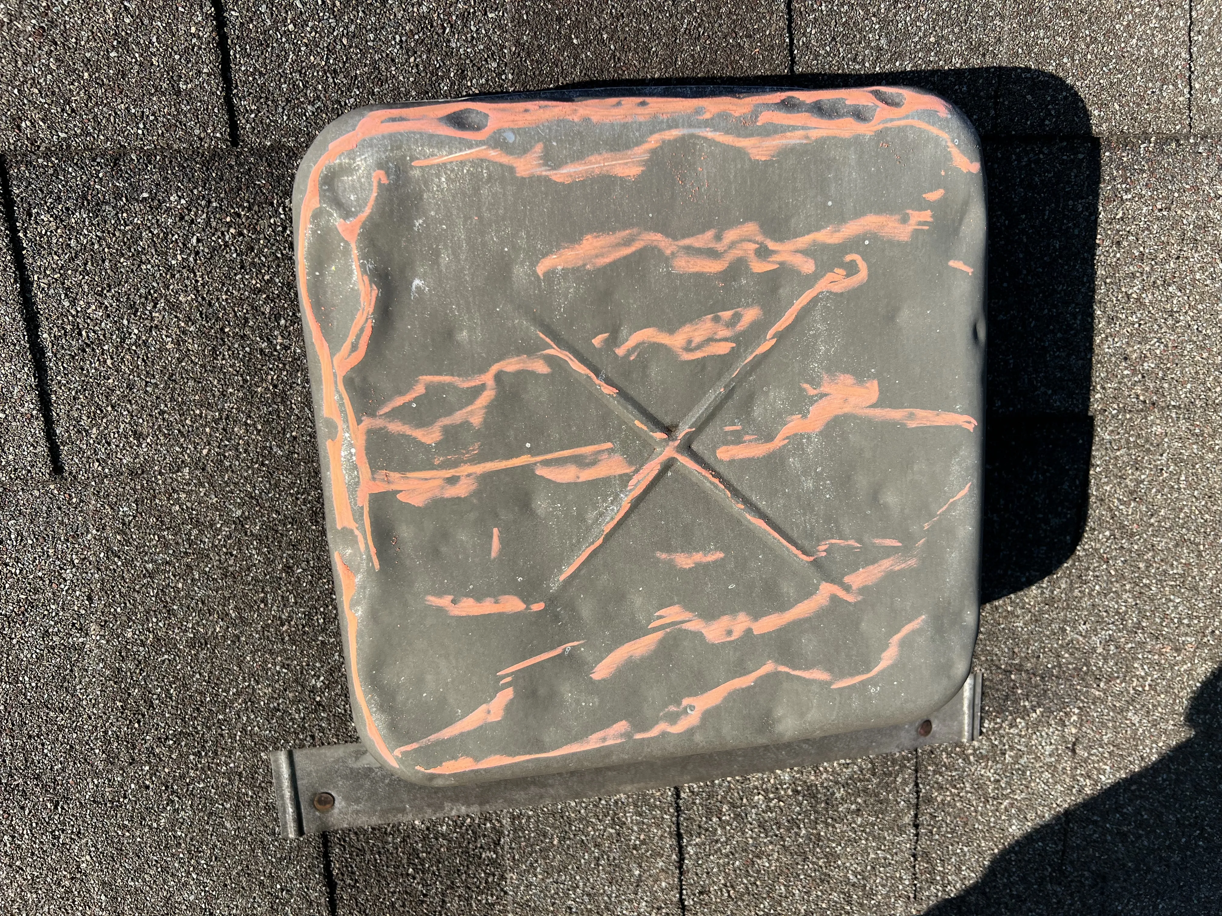 Hail-damaged aluminum vent with orange spray paint X — instantly reads as hail damage