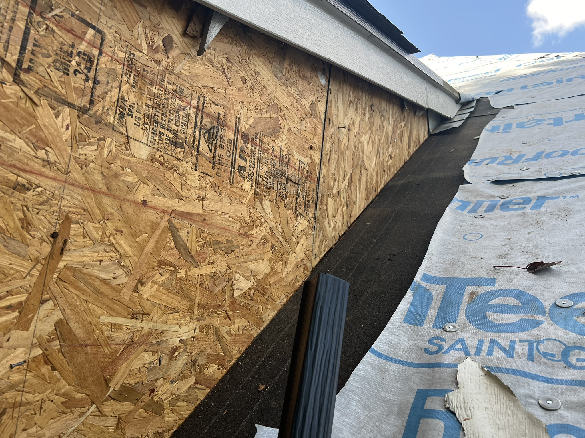 New OSB decking with drip edge and underlayment installed, blue sky background