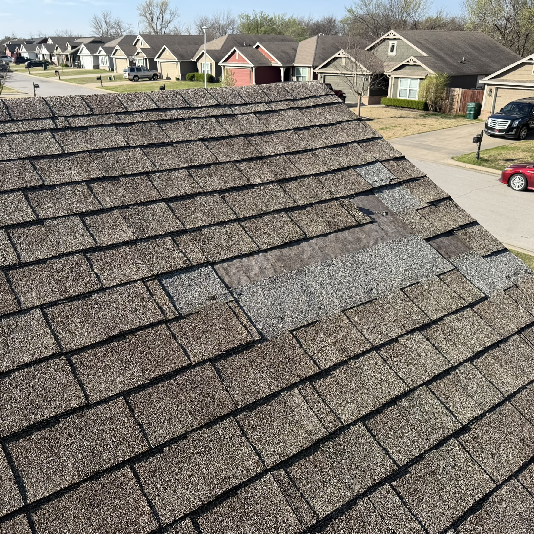 Missing shingles exposing felt paper on Tulsa neighborhood roof