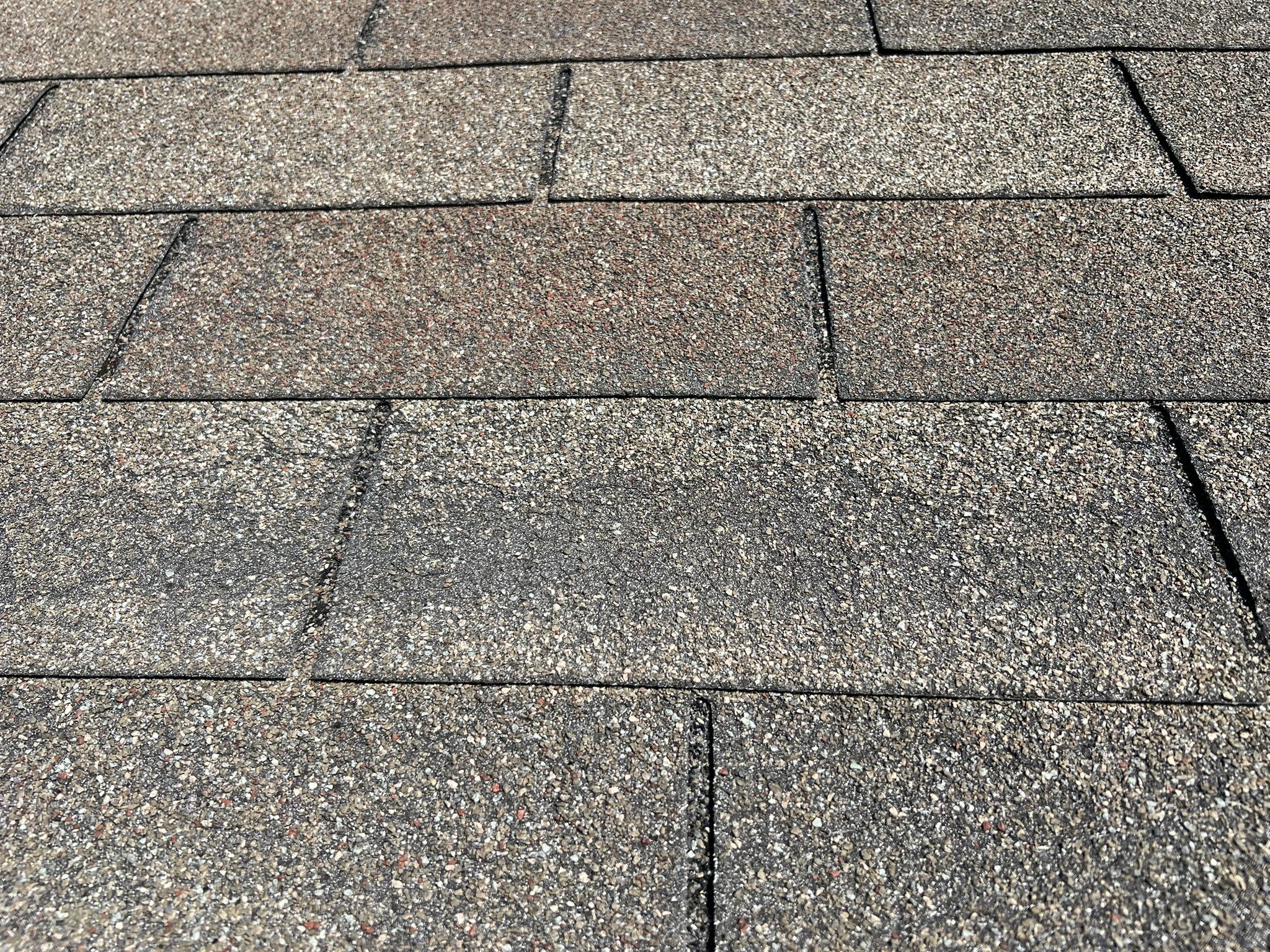Close up of granule loss showing patchy color variation across shingle surface