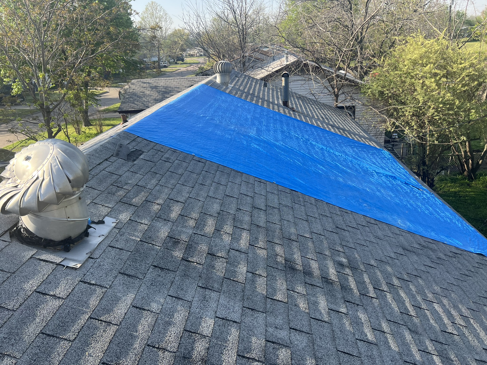 Blue emergency tarp covering storm damaged roof in Tulsa