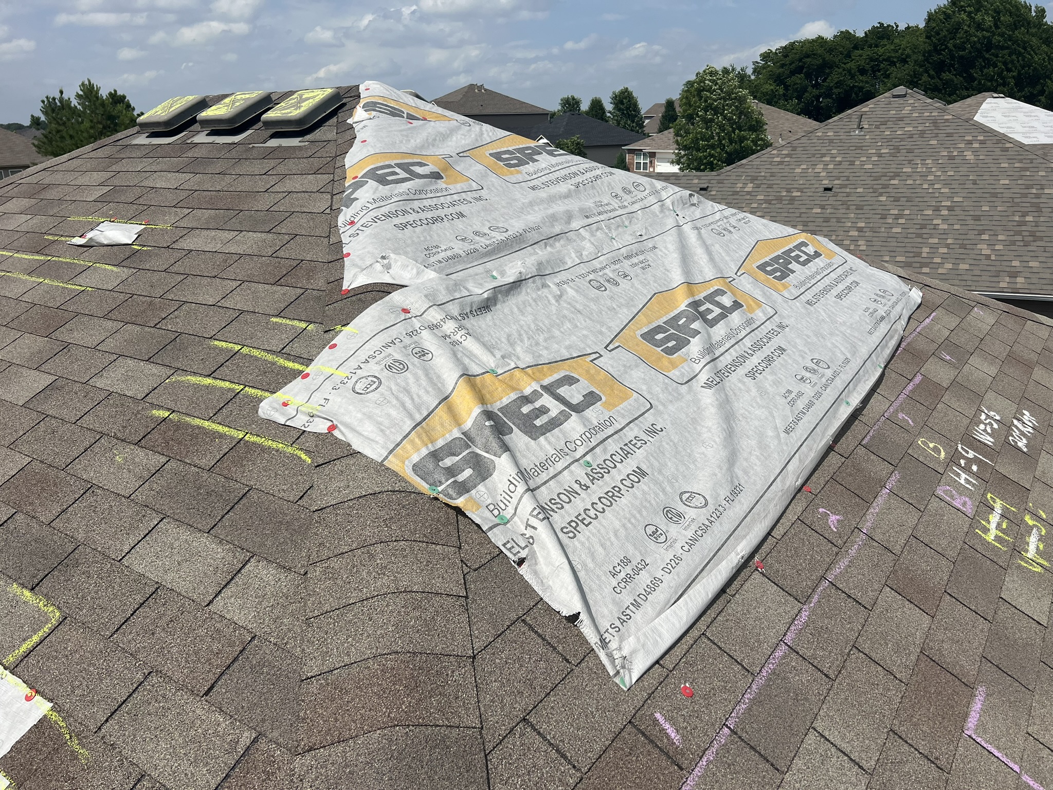 Emergency tarp peeling back on damaged Tulsa roof exposing felt paper