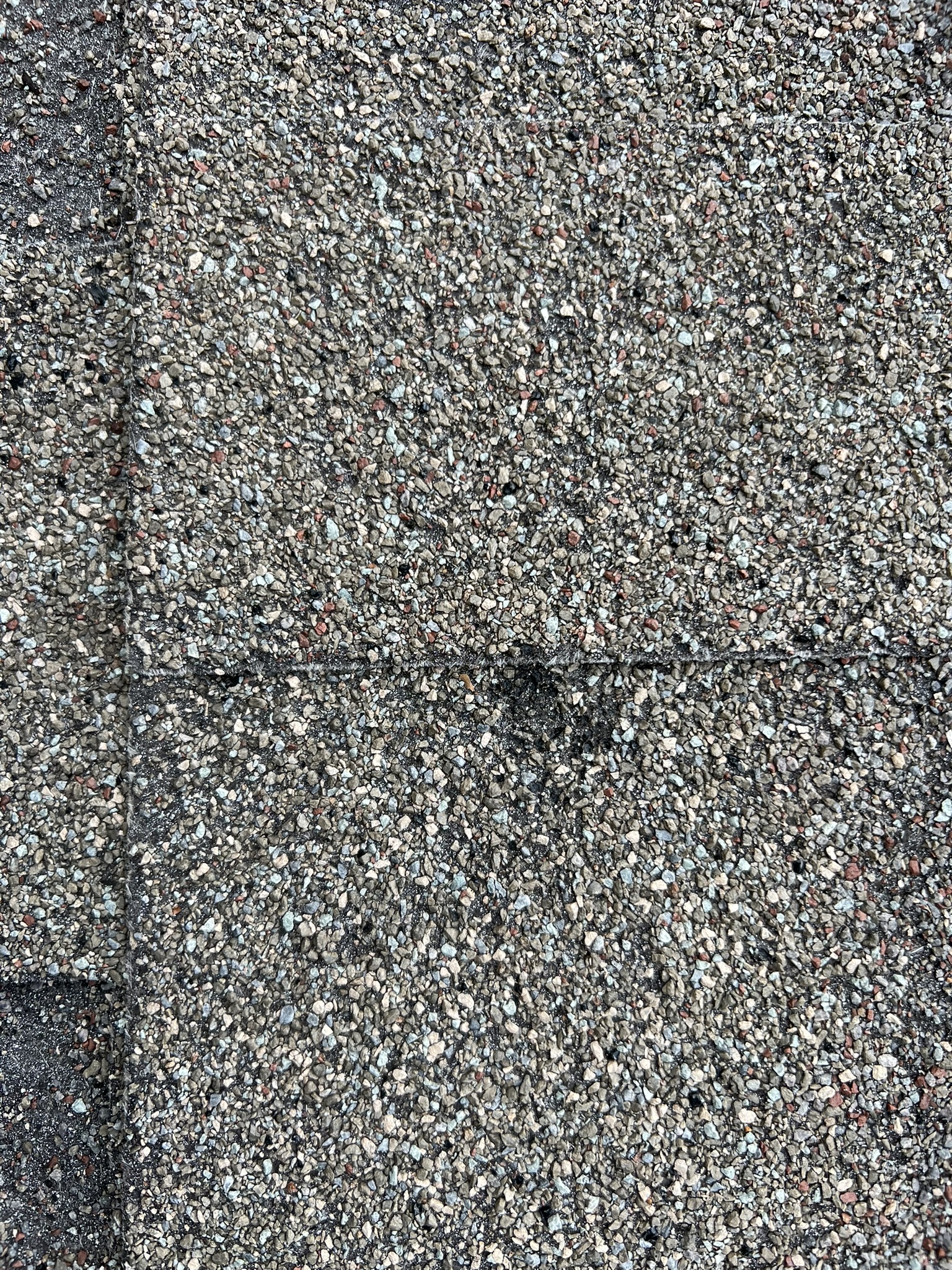 Close up of hail impact crater on asphalt shingle surface