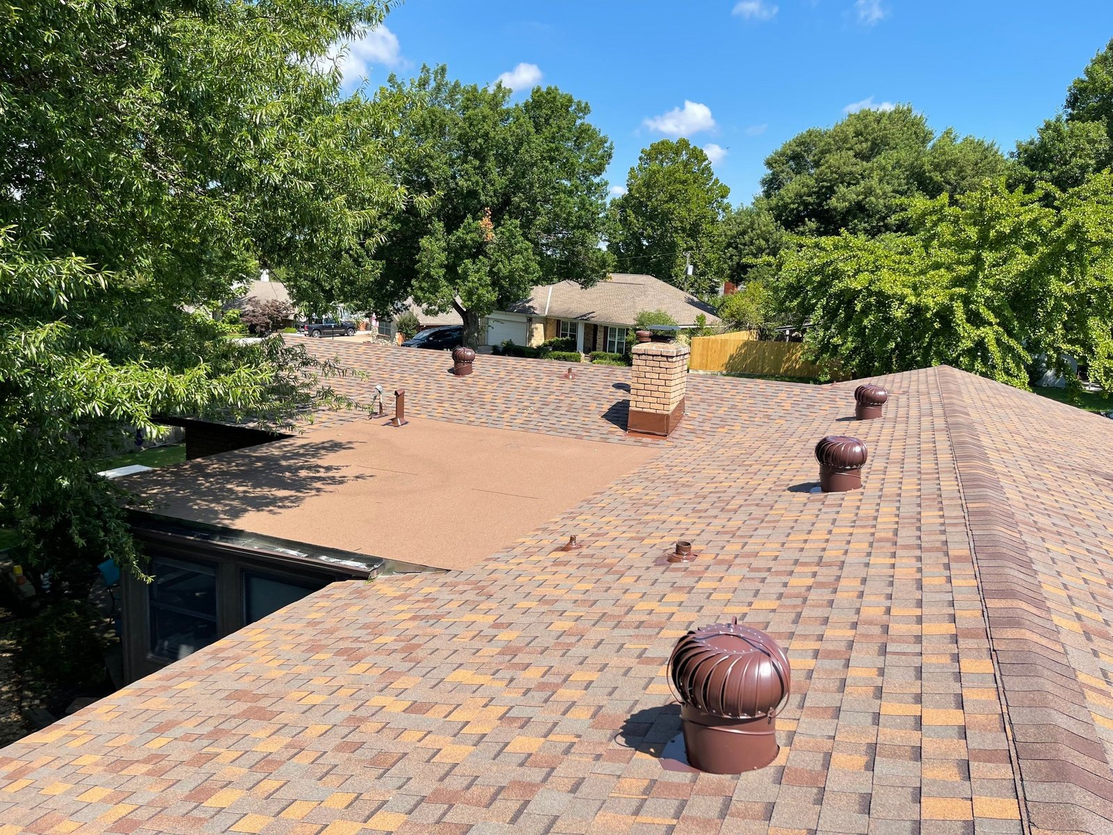 Multiple turbine vents on a large roof with chimney, blue sky